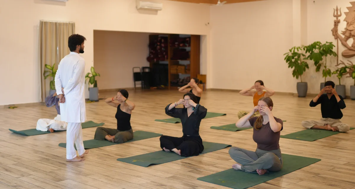 Teacher leading a small group practice in the ashram yoga hall