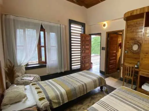 Ashram room with twin beds, large windows and wooden doors