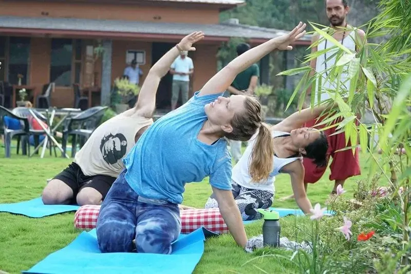 Students practising a seated side bend on the lawn during class