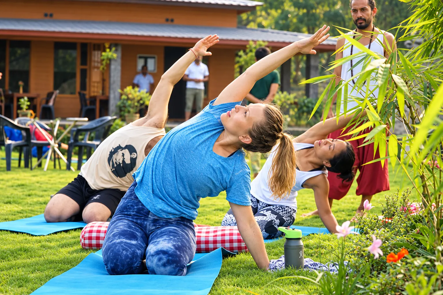 Students stretching in a side-angle pose on the lawn at Abhayaranya Yoga Ashram