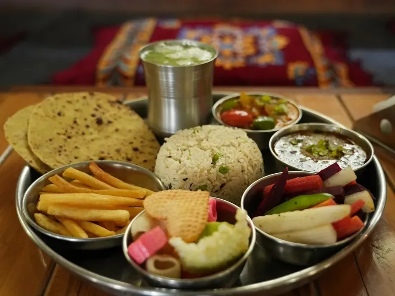 Vegetarian thali with flatbread, rice, dal, salad and fresh vegetables served on a steel plate