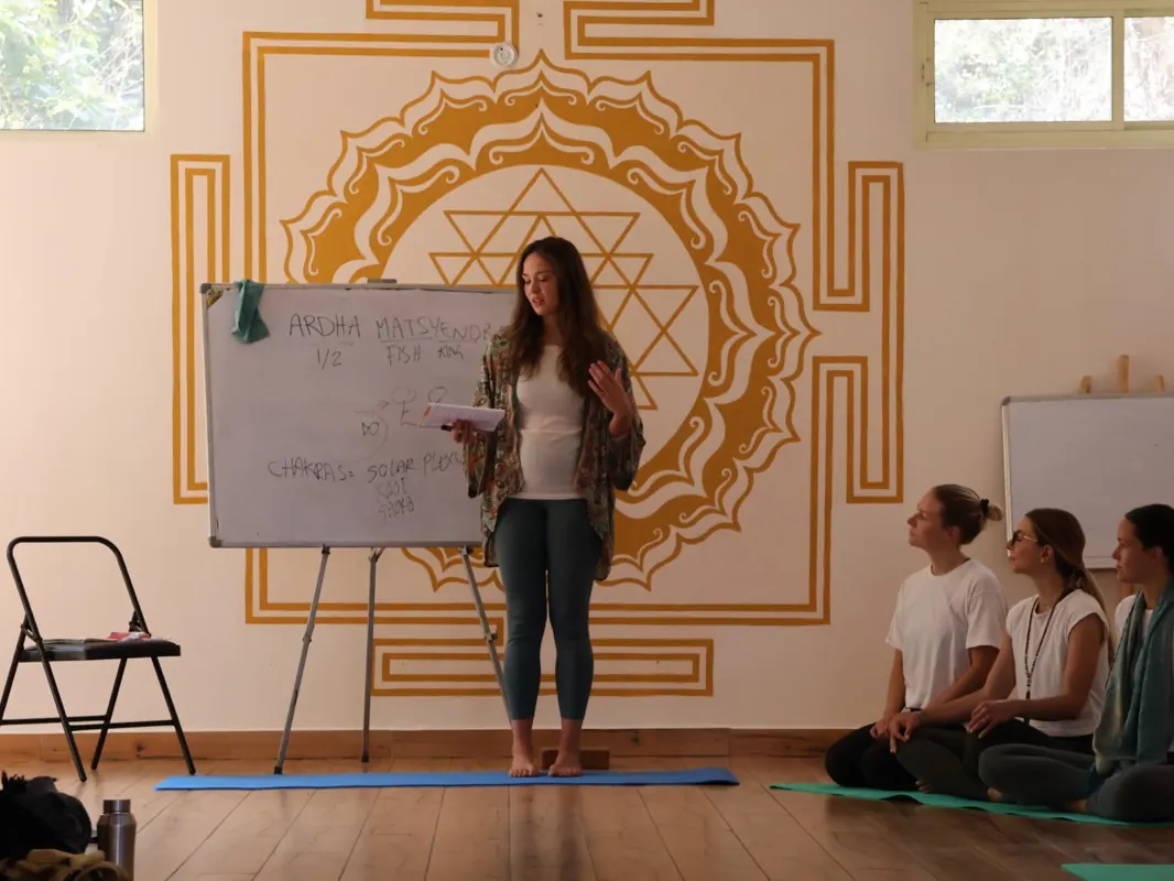 A teacher leads a philosophy class at a whiteboard in front of a Sri Yantra mural