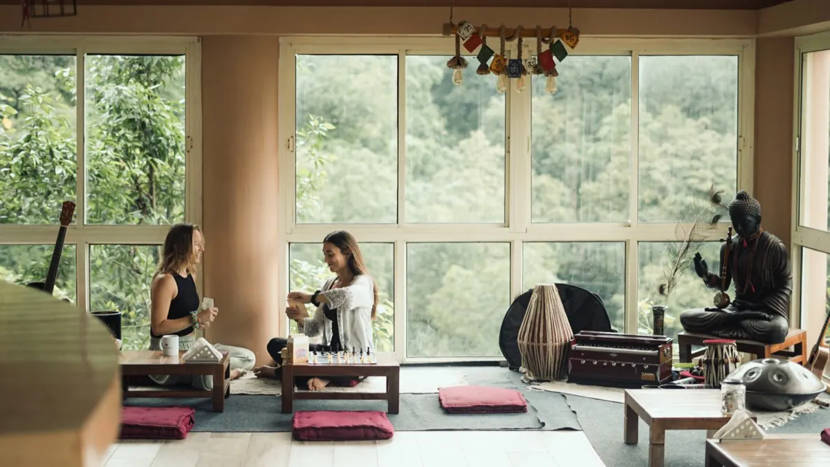 Two students in conversation over tea in the forest view lounge of the ashram