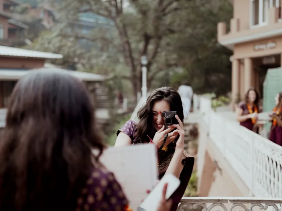 A graduate takes a photo of a friend on the ashram bridge on their last day
