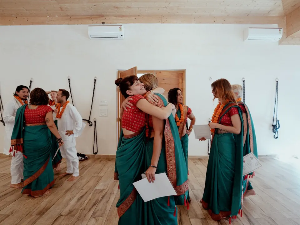 Two graduates hug after the graduation ceremony in the yoga hall