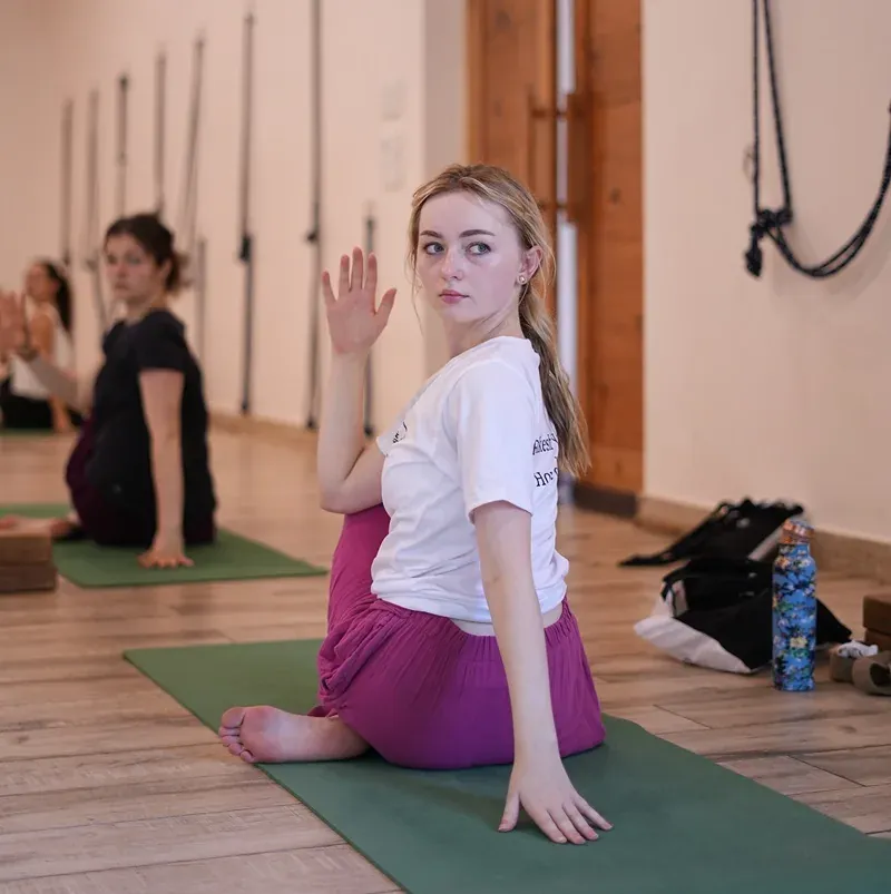 Student in a seated twist on a mat in the ashram yoga hall