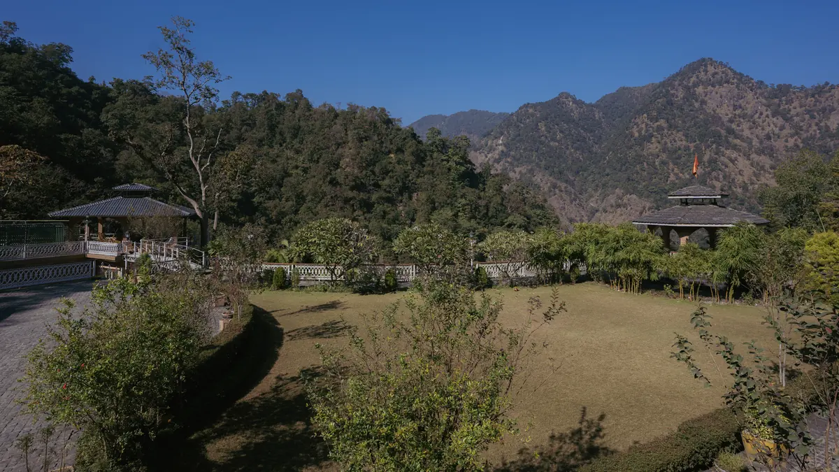 The ashram lawn and garden pavilions empty beneath the mountains