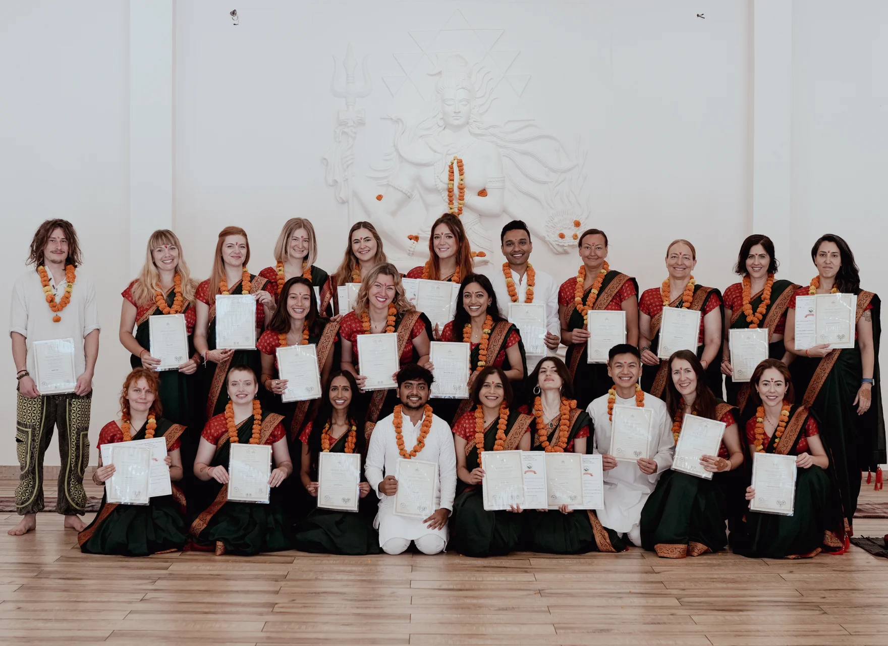 Graduating students in teal saris with marigold garlands