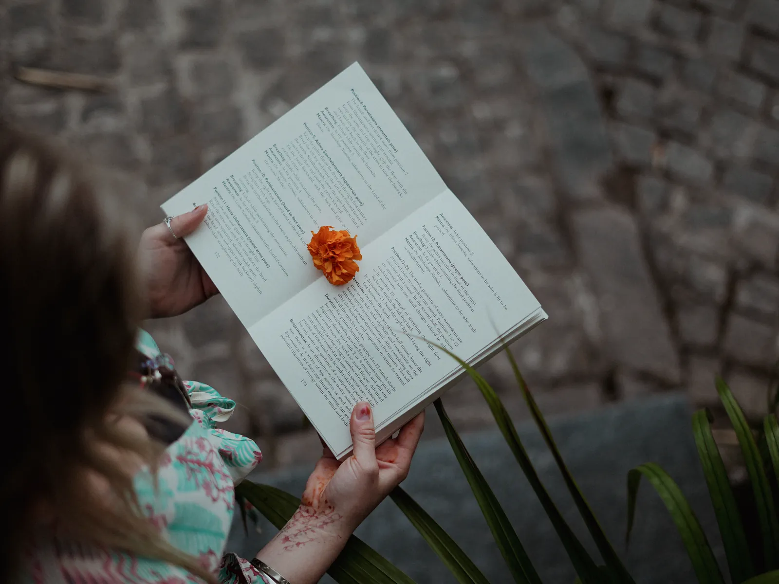 A student holds open a yoga text with a marigold resting on the page at the ashram in Rishikesh