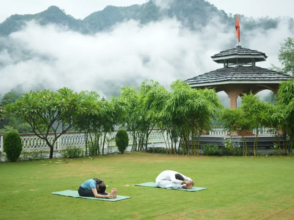 Two guests rest in child's pose on the lawn as clouds lift off the hills
