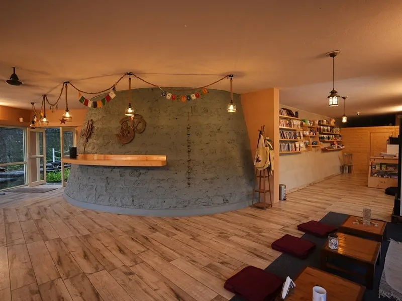 Ashram lounge with a curved wooden counter, bookshelves and floor seating